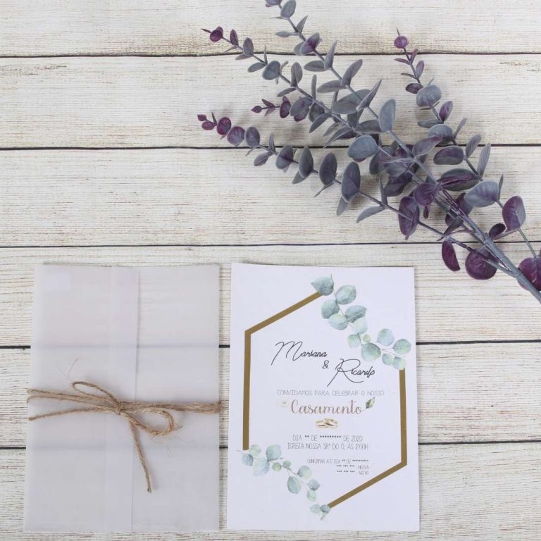 Convite de casamento com design elegante e detalhes em tons de azul e dourado, acompanhado de ramo de eucalipto roxo sobre uma superfície de madeira clara.