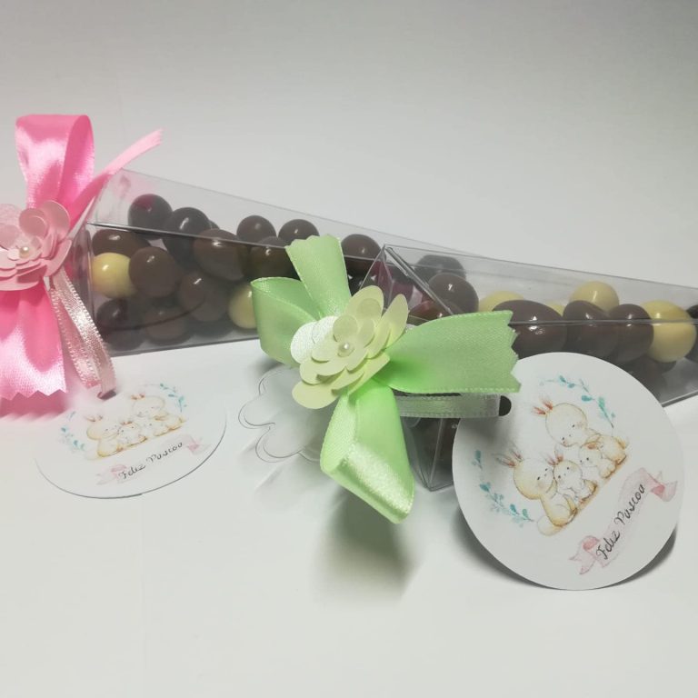 Imagem de uma caixa de chocolates em forma de triângulo, decorada com laços rosa e verde, com etiquetas de papel com desenhos de ursinhos de pelúcia e mensagens de feliz Páscoa.