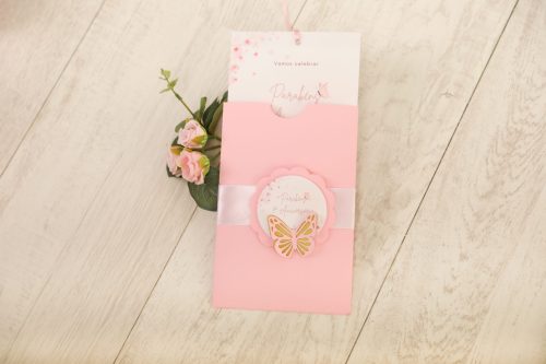 Conjunto de acessórios de cabelo rosa com borboleta, acompanhado de uma flor rosa, sobre uma superfície de madeira clara.