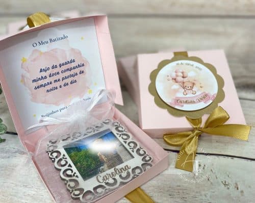 Caixa de lembrança de batizado com uma foto, mensagem e decoração delicada em tons de rosa, branco e dourado.