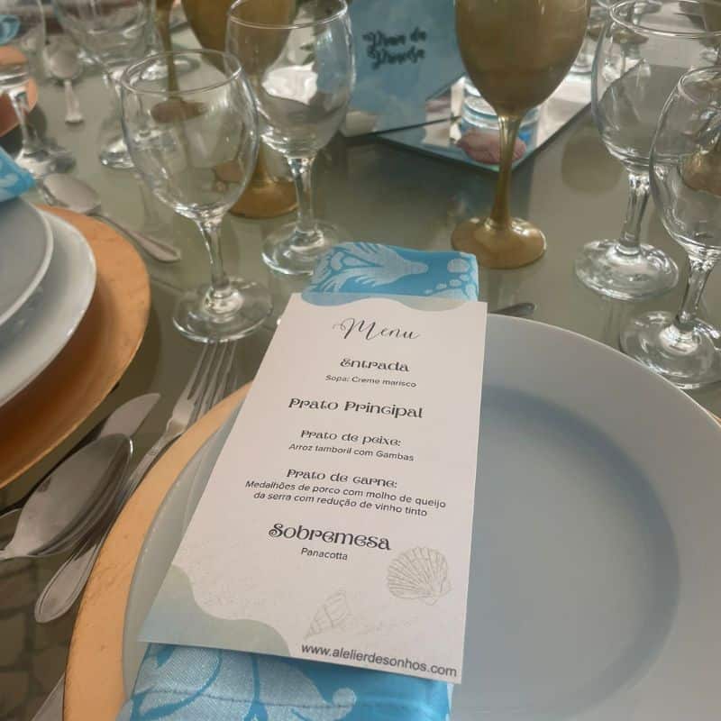 Menu de restaurante com opções de peixe e camarão, incluindo prato principal de peixe, arroz com camarão e sobremesa de panacota, apresentado em uma mesa de jantar elegante com taças e utensílio.