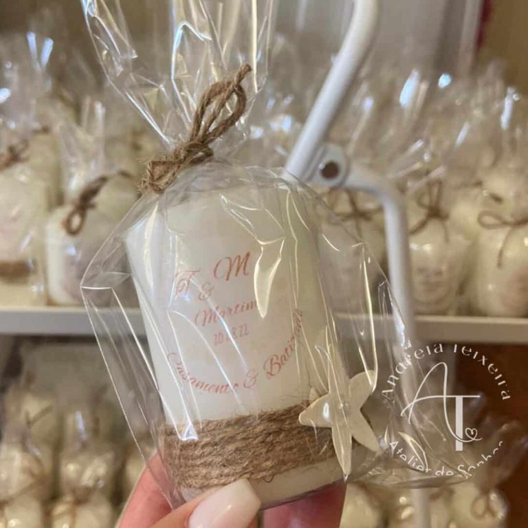 Vela artesanal embrulhada em celofane transparente, decorada com laço de juta e uma pequena borboleta de madeira, ideal para lembranças de eventos especiais.