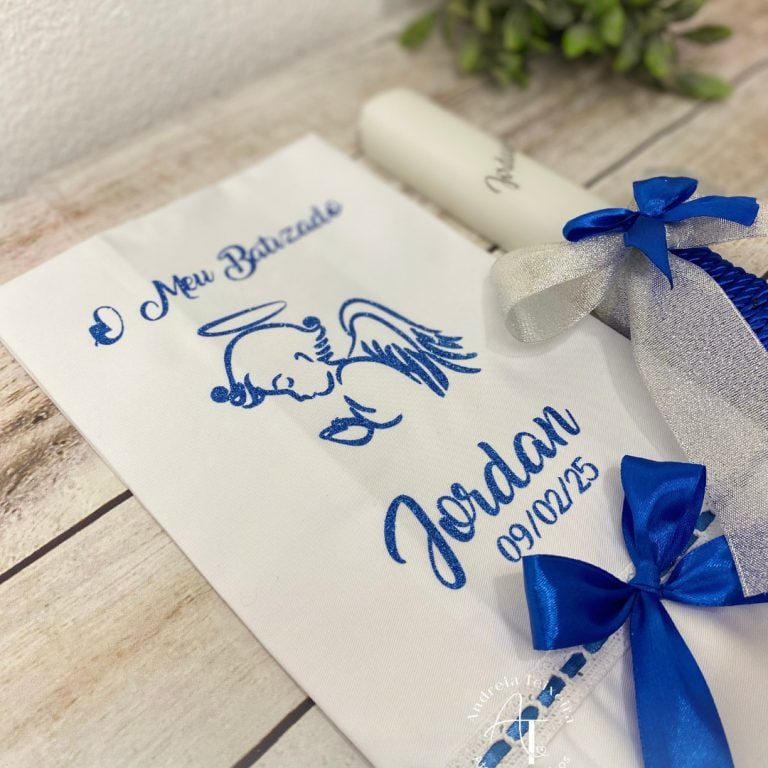 Vela e toalha de batizado personalizadas com anjo azul e laços prateados e azuis.