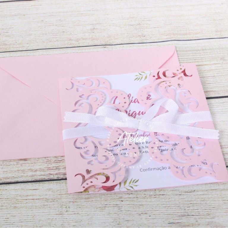 Convite de casamento delicado com laço branco e detalhes dourados, acompanhado de envelope rosa claro, ideal para ocasiões especiais.