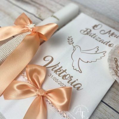 Vela e toalha de batizado personalizadas para a Viktoria com laços pêssego e ilustração de pomba.