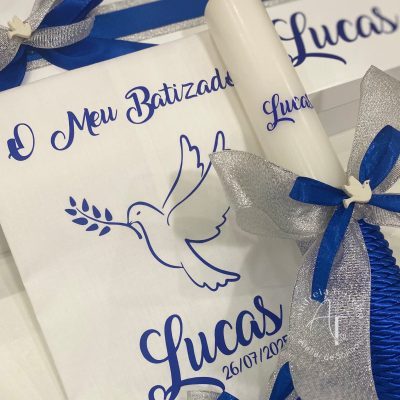 Vela e toalha de batizado personalizadas, com laço azul e prata e ilustração de pomba da paz.