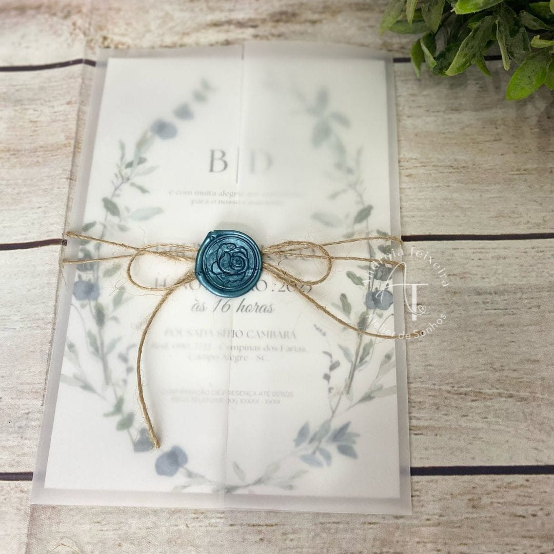 Convite de casamento com design delicado, fita de juta e selo de cera azul, sobre uma mesa de madeira clara, ideal para ocasiões especiais e celebrações românticas.