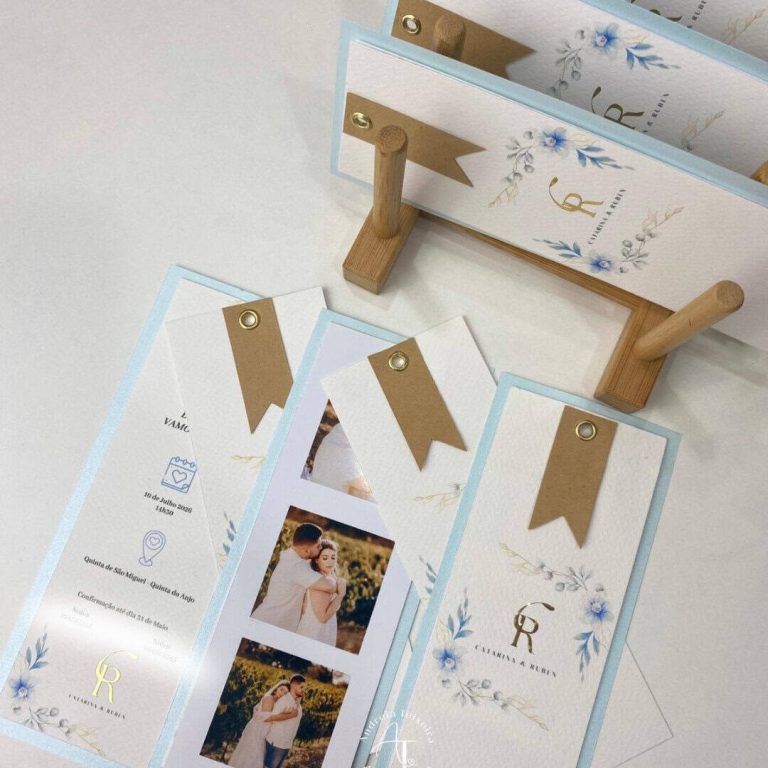 Cadeia de marcadores de papel decorativos com detalhes em azul e dourado, dispostos sobre uma superfície branca, com uma estrutura de suporte de madeira ao fundo.