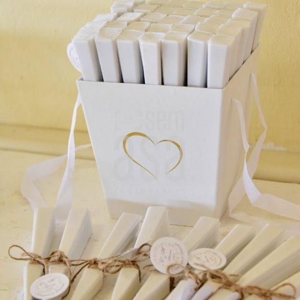 Cadeia de velas brancas em uma caixa decorativa com um coração dourado, acompanhada por várias velas menores amarradas com barbante, ideal para decoração ou celebrações especiais.
