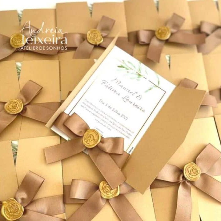 Cadeias de convites de casamento em caixas douradas com laços de fita marrom e selo de cera dourado, com convite central em destaque.