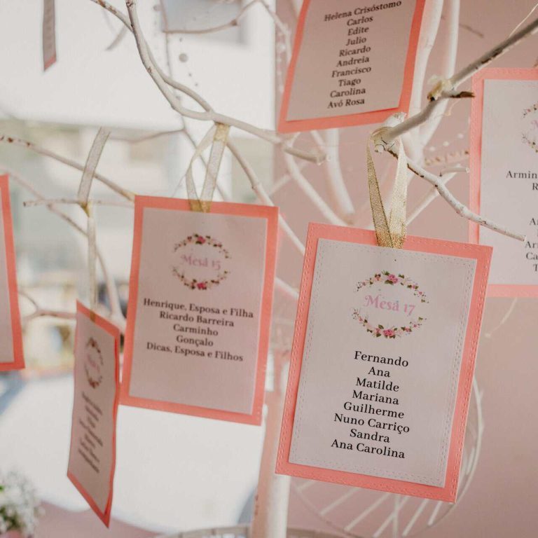 Balde de árvores decorativas com cartões pendurados, cada um com nomes e mensagens, em tons de rosa e branco, ideal para eventos como casamentos ou celebrações familiares.