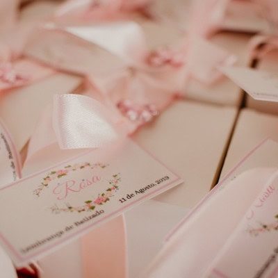 Lembranças de casamento com etiquetas personalizadas e detalhes em rosa, incluindo nomes e data do evento.