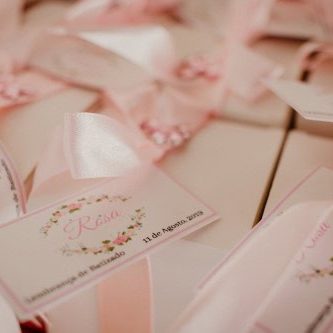 Lembranças de casamento com etiquetas personalizadas e detalhes em rosa, incluindo nomes e data do evento.