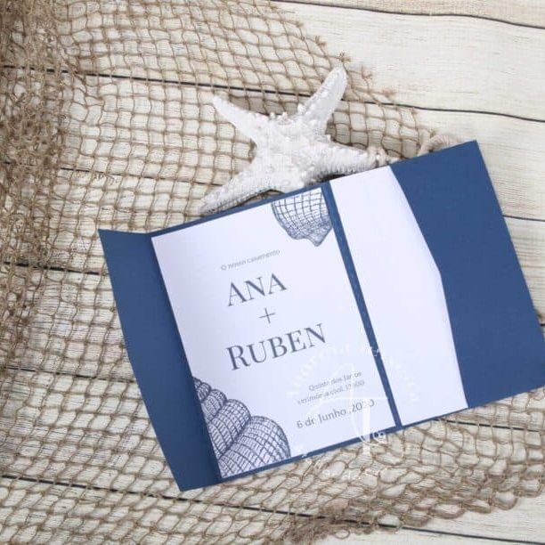 Convite de casamento com nomes Ana e Ruben, decorado com tema náutico, sobre uma rede de pesca e uma estrela-do-mar, em fundo de madeira clara.