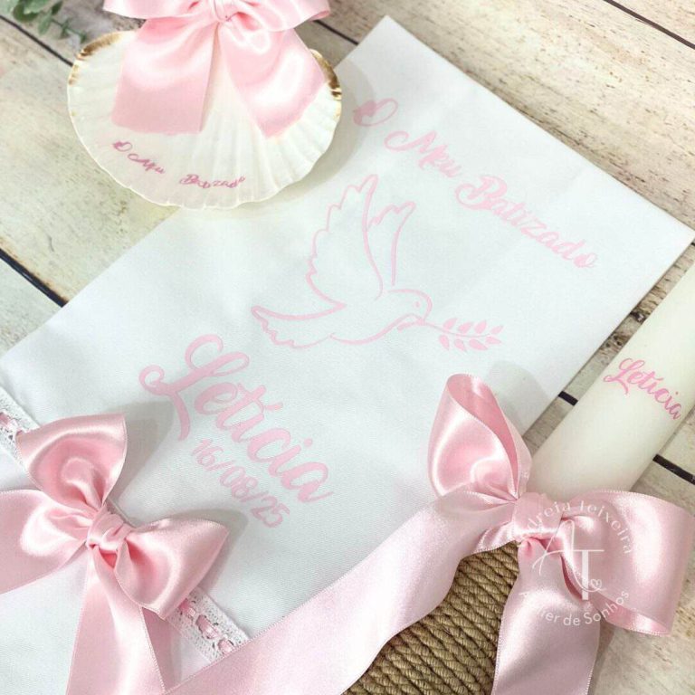 Conjunto de lembranças de batizado com fita rosa, papel decorativo com pomba e mensagem de bênção, ideal para celebração religiosa infantil.